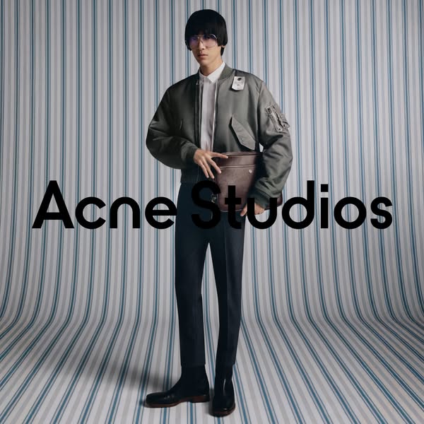 This ad features a full-body shot of a person wearing Acne Studios clothing and carrying an Acne Studios bag. The brand 
