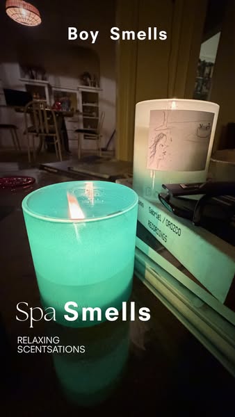 This ad features two lit candles on a reflective surface and promotes Boy Smells candles.
