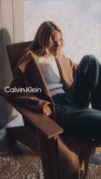 This image ad features a fair-skinned blonde woman sitting in a wooden chair, outside in the snow. She's wearing clo