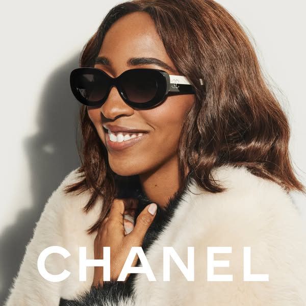 An image ad for Chanel featuring a smiling woman wearing Chanel sunglasses. The ad uses a clean, high-fashion aesthetic.