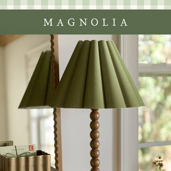 This ad showcases a lamp with a green pleated lampshade and a wooden base, positioned in a room setting with a mirror an