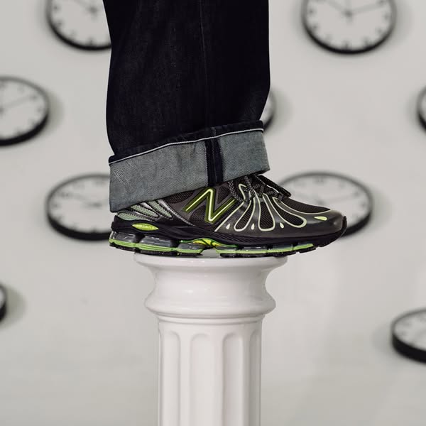 This ad features a New Balance shoe placed on top of a white pillar against a wall covered with clocks. The visual compo