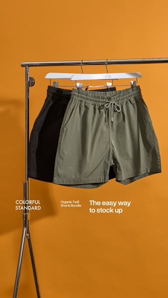 An ad for Colorful Standard's Organic Twill Shorts Bundle shows the shorts hanging from a clothing rack against an o