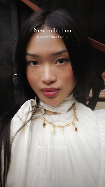An image ad for Ole Lynggaard jewelry featuring a woman with long dark hair wearing a necklace from their Bird Family co
