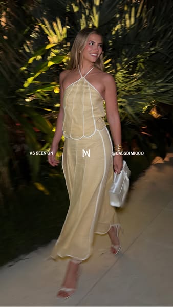 An image ad featuring a blonde woman wearing a cream-colored dress, styled in a lifestyle shot. The ad highlights the br