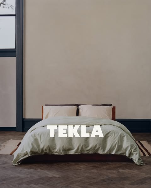 An image showcasing a bed with Tekla brand linens in a minimalist bedroom setting, emphasizing the brand's presence 