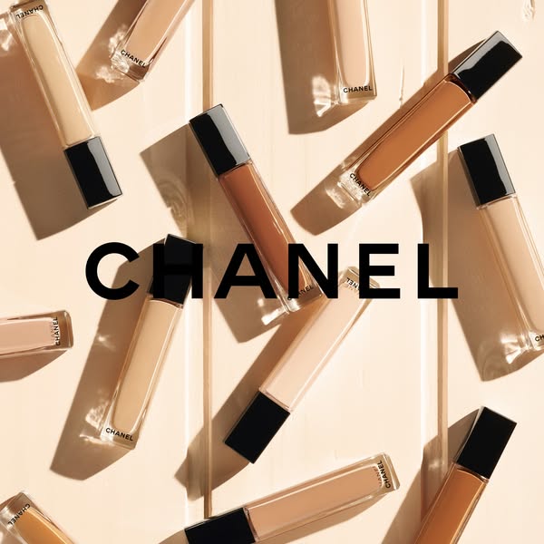 This image ad showcases Chanel concealer products in various shades, presented in an artful, flat lay arrangement on a n