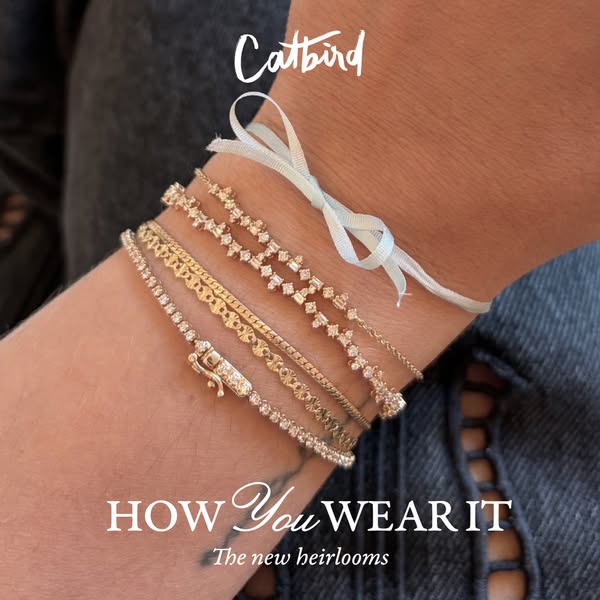 This Meta image ad for Catbird showcases a close-up of a wrist adorned with multiple gold bracelets. The ad emphasizes h