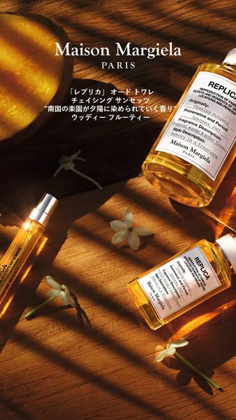 This ad features a flatlay of Maison Margiela's Replica 'Chasing Sunset' fragrance. The image includes the f