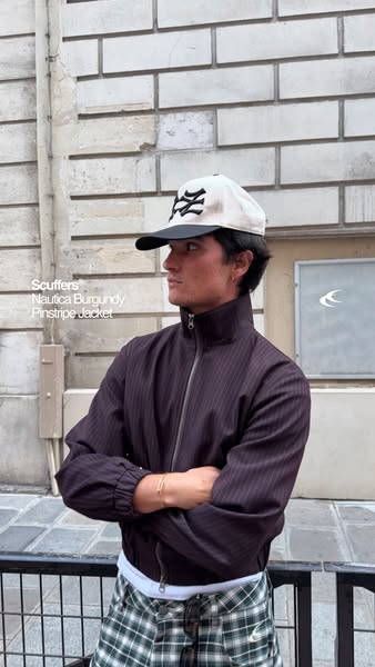 An outdoor shot of a male model wearing a brand's jacket and hat, along with pants that are not part of the brand