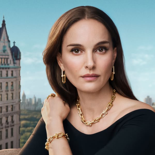 A portrait shot of Natalie Portman wearing the Tiffany Lock collection against a city skyline background.