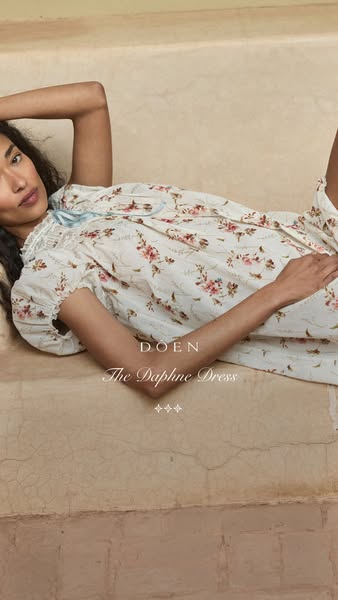 This ad features a woman in a vintage-inspired dress from the brand Doen. She is laying on a neutral surface, showcasing