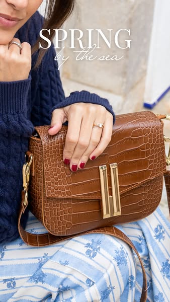 This image ad showcases a brown crossbody bag worn by a woman in a lifestyle setting. The ad uses a soft color palette a