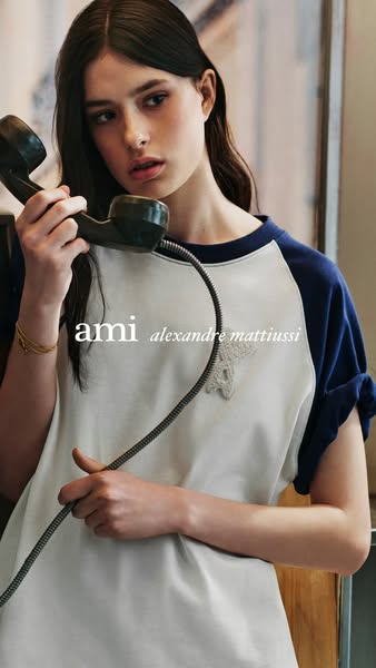 This ad features a woman wearing a two-tone raglan tee with a star logo while holding a black landline telephone. The br