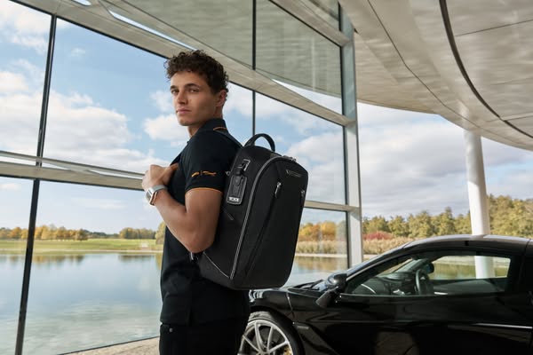 This image promotes a sleek, black TUMI backpack in collaboration with McLaren, positioned as a luxury item suitable for