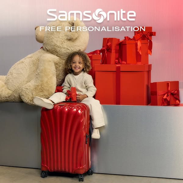 This ad features a child sitting on a red Samsonite suitcase, surrounded by gifts and a large teddy bear, promoting free