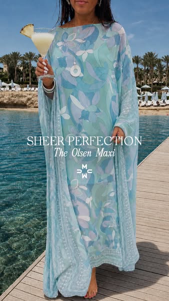This ad showcases a woman wearing a flowing, floral-patterned maxi dress near a tropical beach, conveying a sense of lux