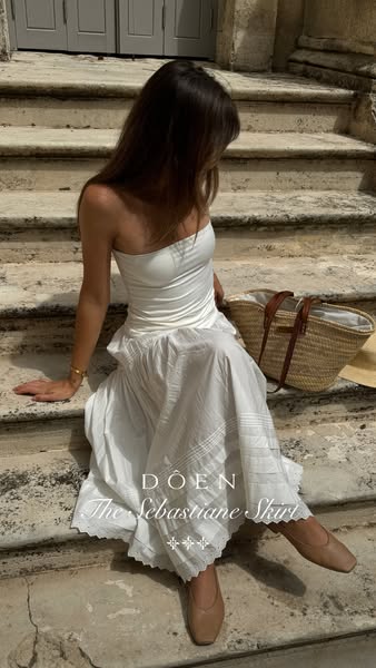 This ad features a woman sitting on stone steps wearing a white skirt and top from the brand DOEN. The ad is designed to