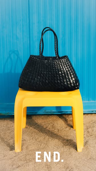 This is a simple product shot for a black woven tote bag.