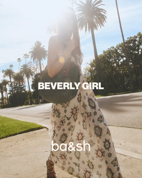 This image ad showcases a woman wearing a ba&sh dress and carrying a ba&sh bag in an outdoor setting.