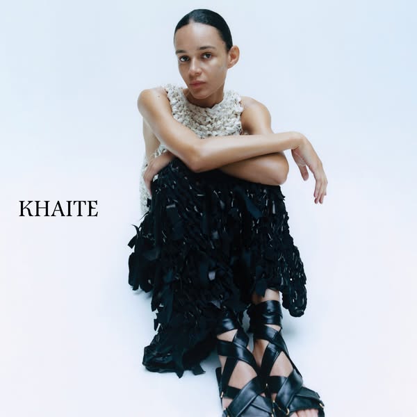 This ad features a model wearing clothing and shoes from KHAITE. The model is posed against a white backdrop with the br