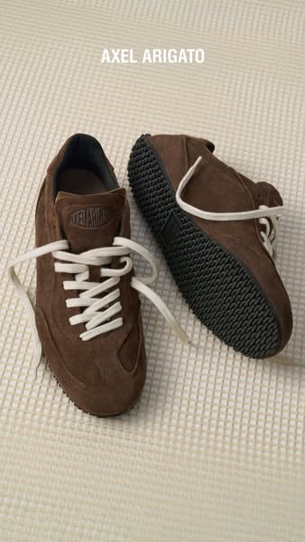 This image ad showcases brown Axel Arigato sneakers against a textured background.