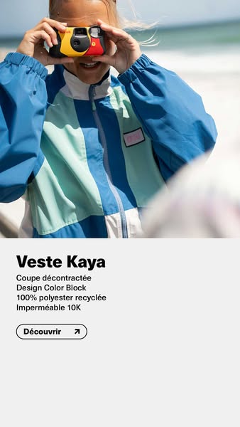 An image ad for the Veste Kaya jacket. The ad features a person in the jacket holding up a camera. The background is a b