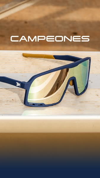 Image ad showcasing a pair of blue-framed sunglasses on a light brown wooden surface. The sunglasses have reflective gol