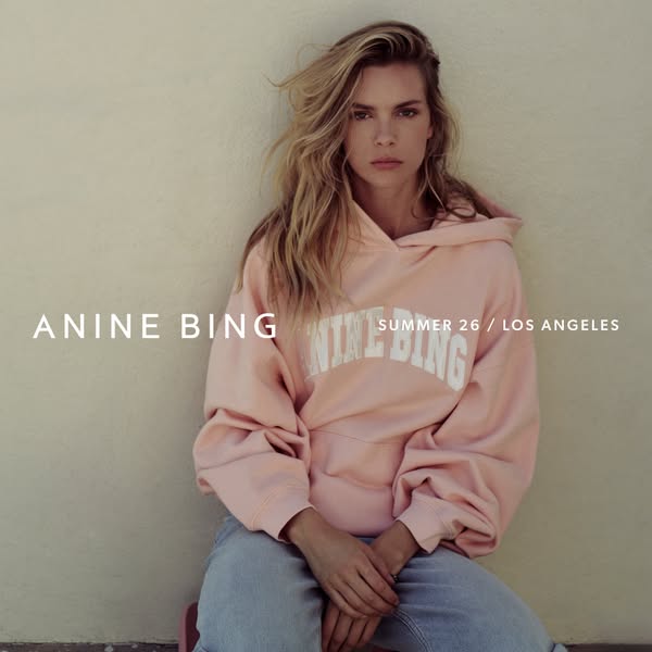 This image ad for Anine Bing features a model wearing a pink hoodie with the brand name on it. The ad emphasizes the bra