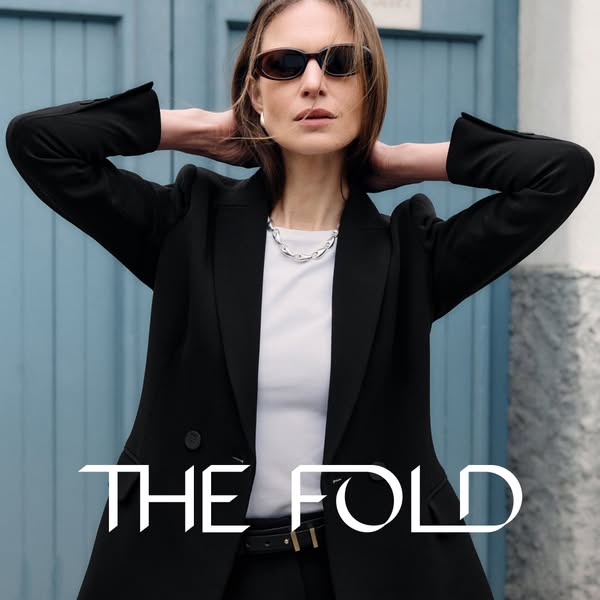 A woman is seen wearing a blazer and necklace. The ad is for The Fold.