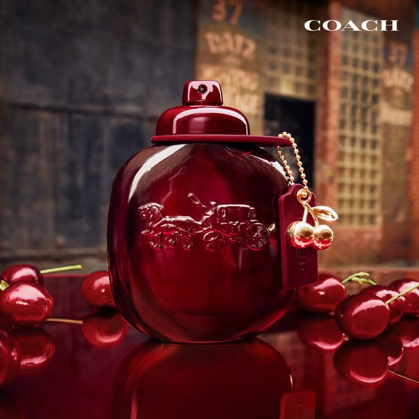 A product image showcases Coach's Cherry perfume. The perfume bottle is photographed up close, surrounded by fresh c