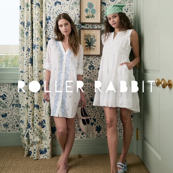 This image ad features two women modeling Roller Rabbit clothing in a room with floral wallpaper and decor, showcasing t