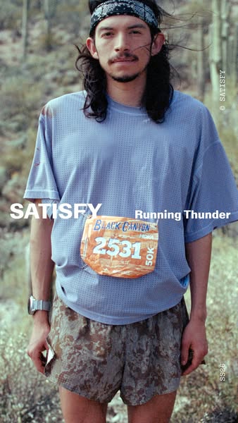 This image ad features a male runner wearing Satisfy brand apparel during what appears to be an endurance race. The over