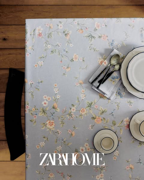 This Zara Home ad showcases a beautifully set table featuring a floral tablecloth, elegant plates, cups, cutlery, and na