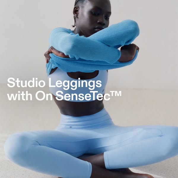The image shows a black woman sitting on the ground wearing the Studio Leggings with On SenseTec™.