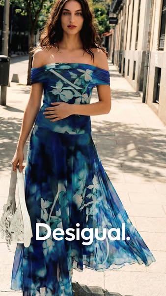 This ad features a stylish woman wearing a Desigual dress with a floral design. The ad is set on a European city street.