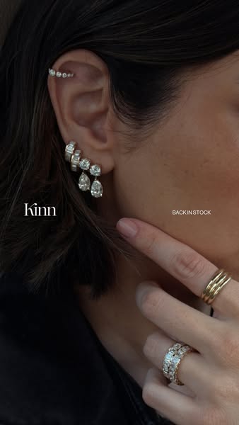 This ad highlights jewelry from Kinn, showcasing earrings and rings worn by a person with dark hair.