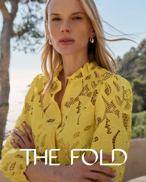 This image ad features a woman wearing a yellow lace top from The Fold. The ad showcases the brand's clothing in a n