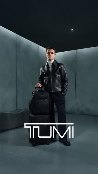 An image ad showcases TUMI luggage. A man, potentially a celebrity, stands with a TUMI backpack placed on top of TUMI lu