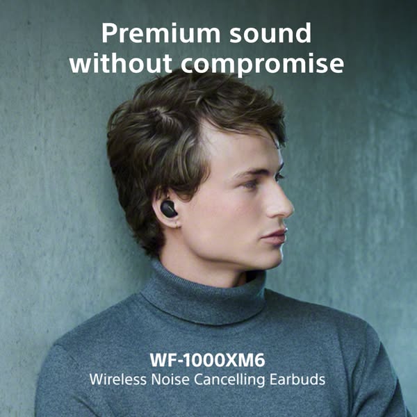 A close up shot of a man wearing wireless noise cancelling earbuds.