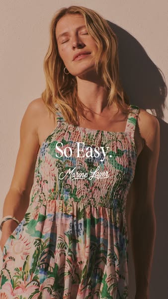 This ad for Marine Layer features a woman wearing a floral print dress in the sunlight.