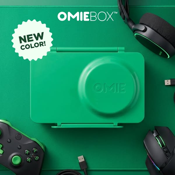 This still image ad showcases OmieBox's new color variant with lifestyle elements like a gaming console controller, 