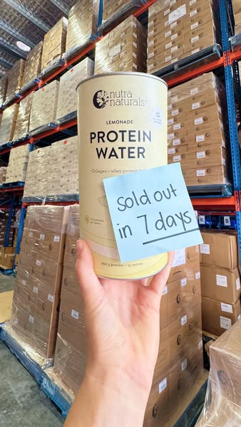 This image ad features a can of lemonade flavored protein water being held in front of a warehouse full of product. A st