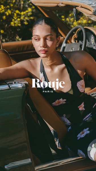This image showcases a woman sitting in a car wearing a dress from the brand Rouje Paris.