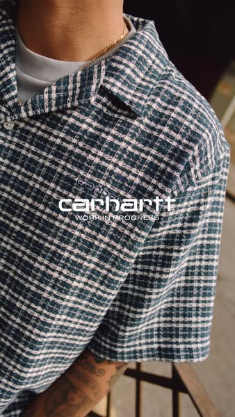 This ad features a close up shot of a person wearing a Carhartt Work In Progress flannel shirt. The brand logo is in the