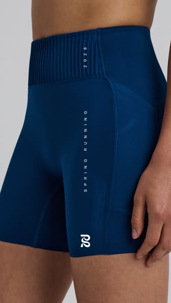 The ad features a close up shot of a person wearing blue Spring Running 2026 athletic shorts. The background is a solid,