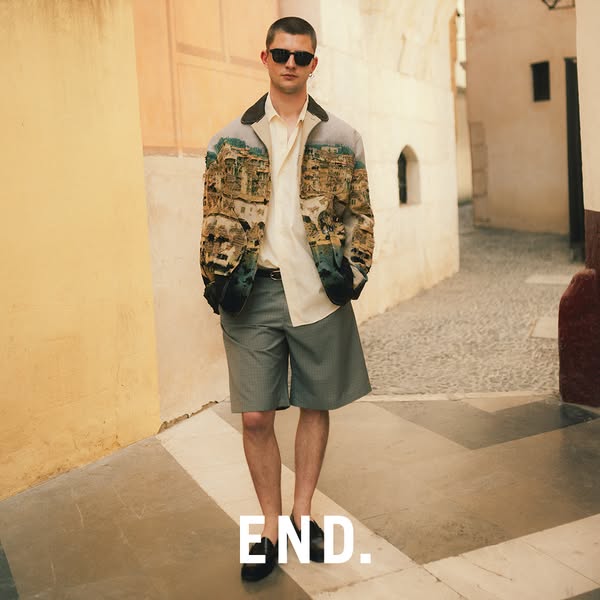 This ad features a man wearing a patterned jacket and shorts while standing on a cobblestone street. The END. logo is su