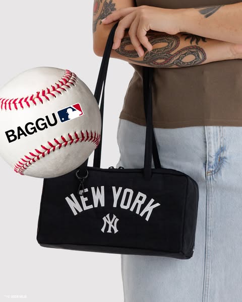 This ad features a New York Yankees BAGGU duck bag, held by a person with arm tattoos. Next to the bag is a baseball wit