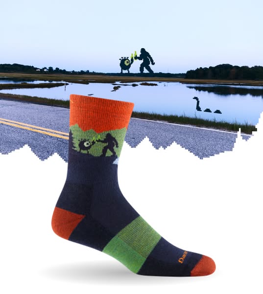 This image ad features a single colorful sock with a playful design superimposed against an outdoor landscape scene. The