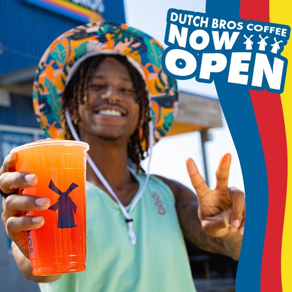 A young man is holding a Dutch Bros drink. In the image is text that says "Dutch Bros Coffee Now Open". The im